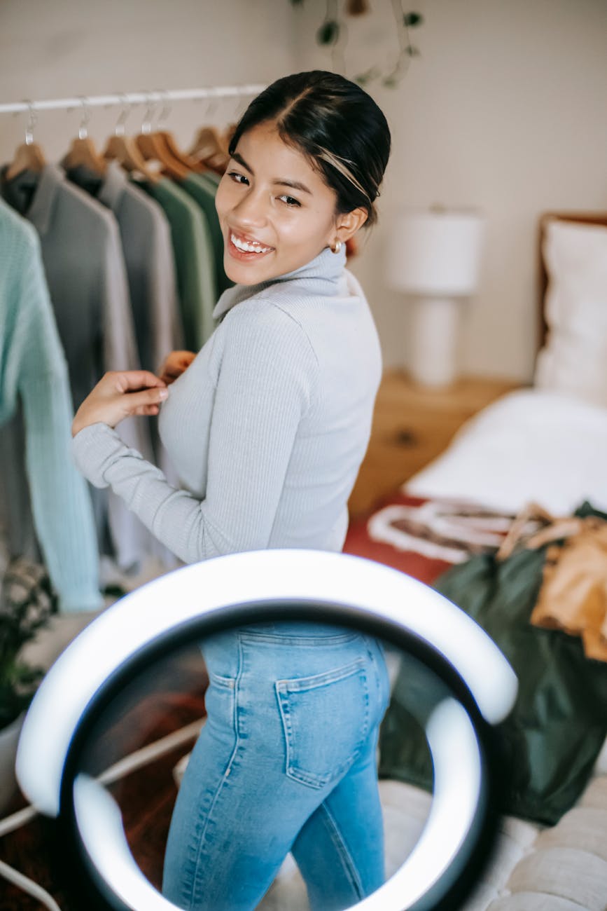 positive ethnic woman demonstrating outfit near light lamp
