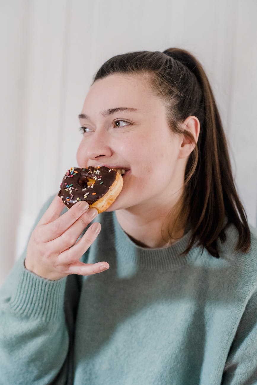 positive woman eating sweet delicious donut