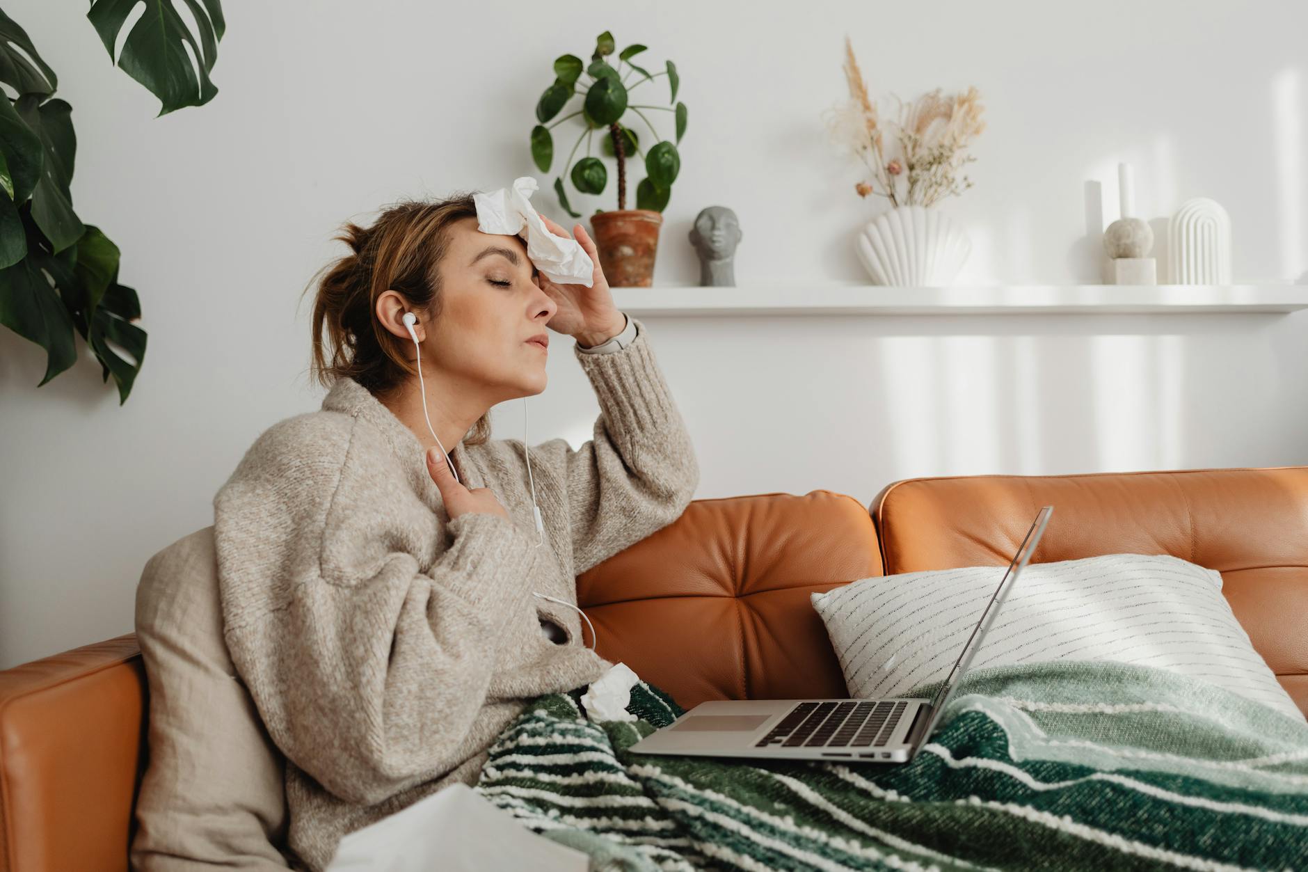 perimenopause woman sitting on the couch wiping her sweat with tissue