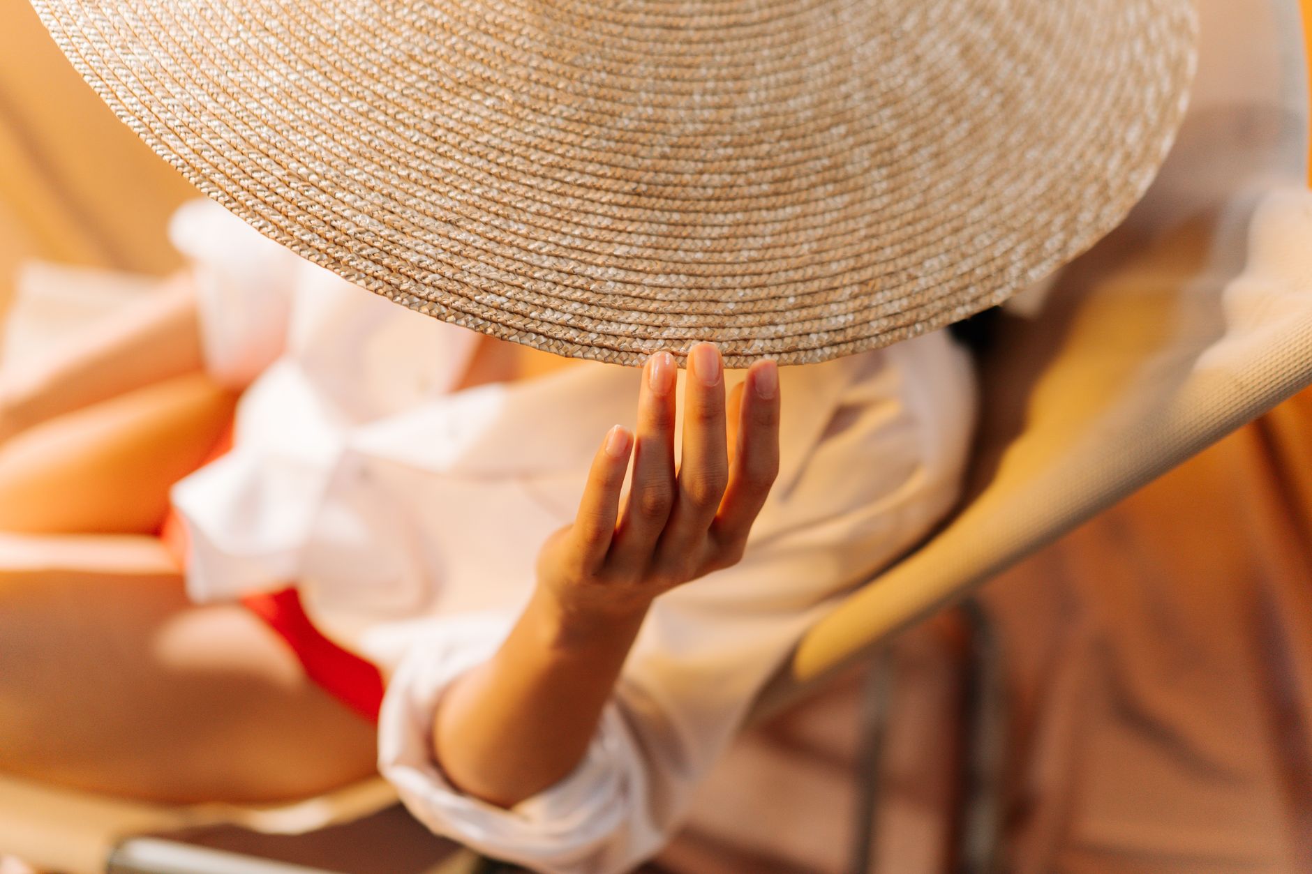 close up shot of a person s hand touching a straw hat
